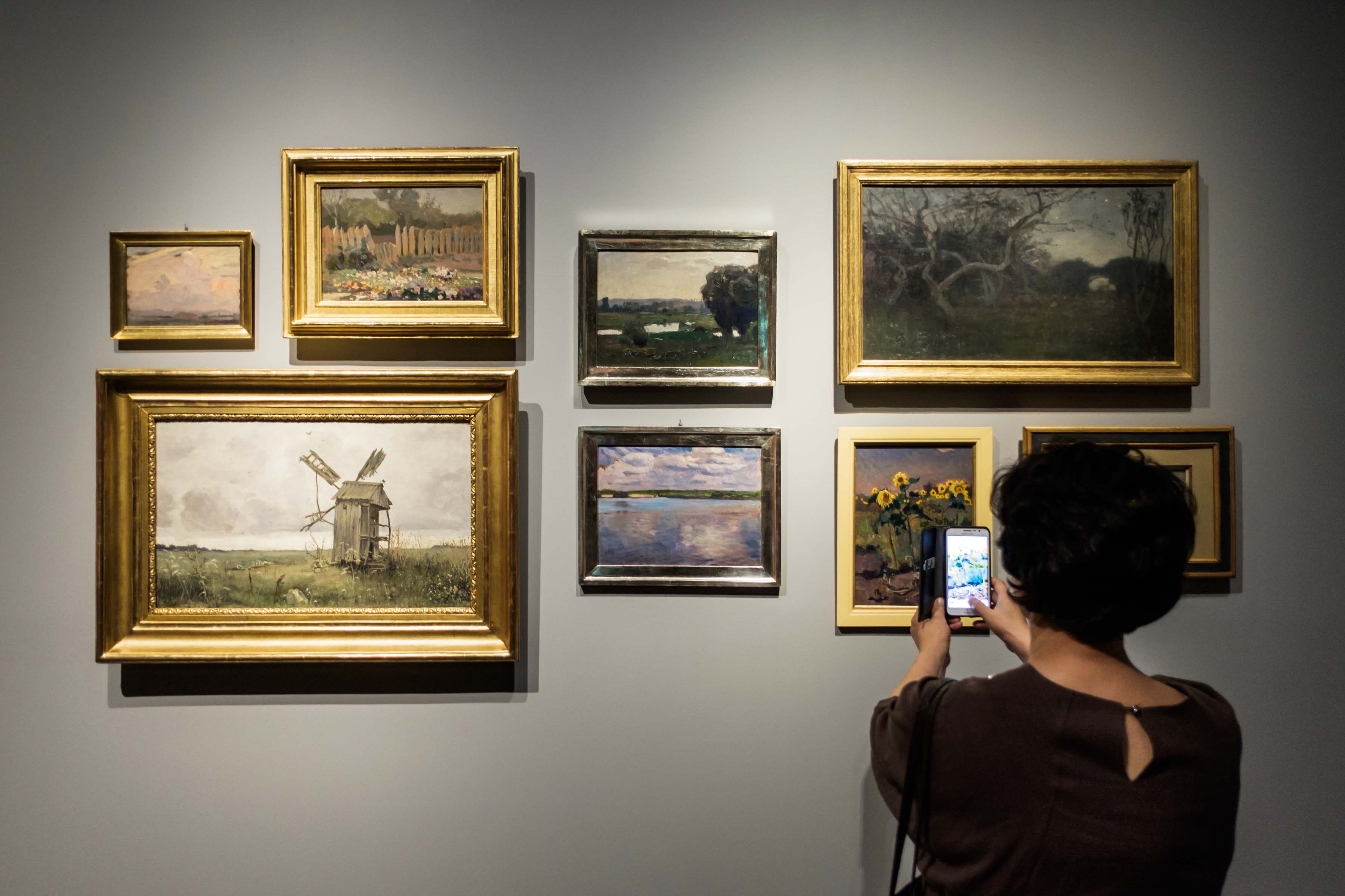 Visitor photographing a salon wall of paintings at the National Museum of Korea