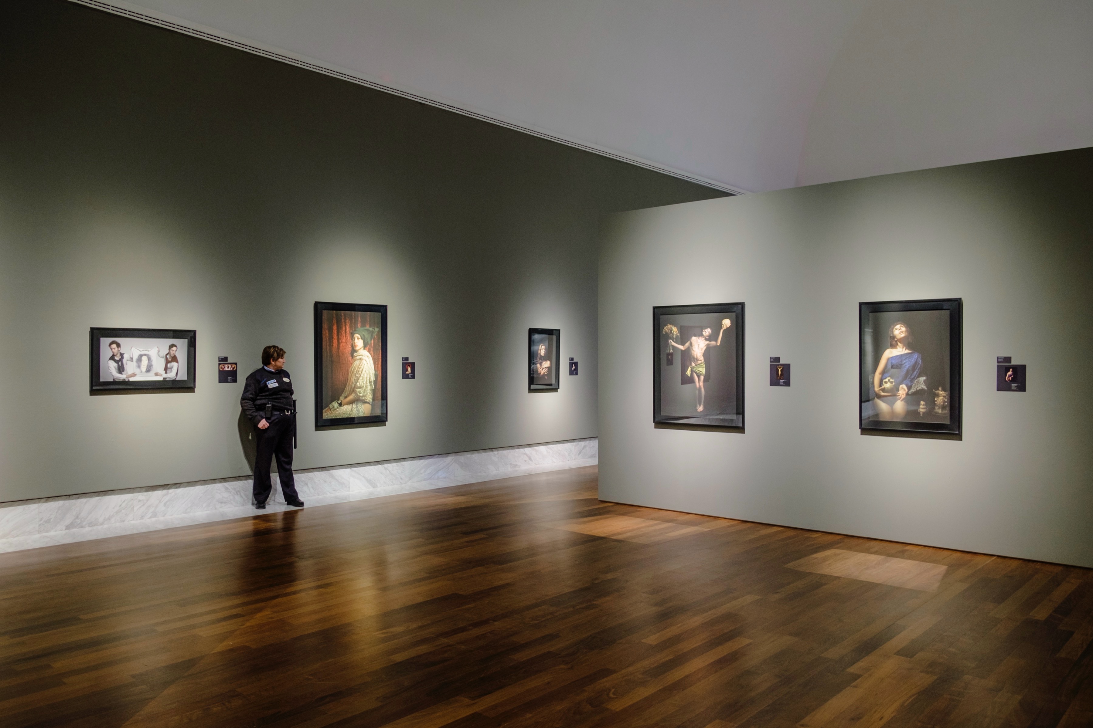 Paintings displayed in a dark-walled museum gallery